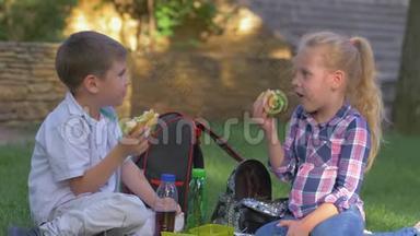 在<strong>校园</strong>里，孩子们在午餐时间坐在草坪上吃三明治，聊天